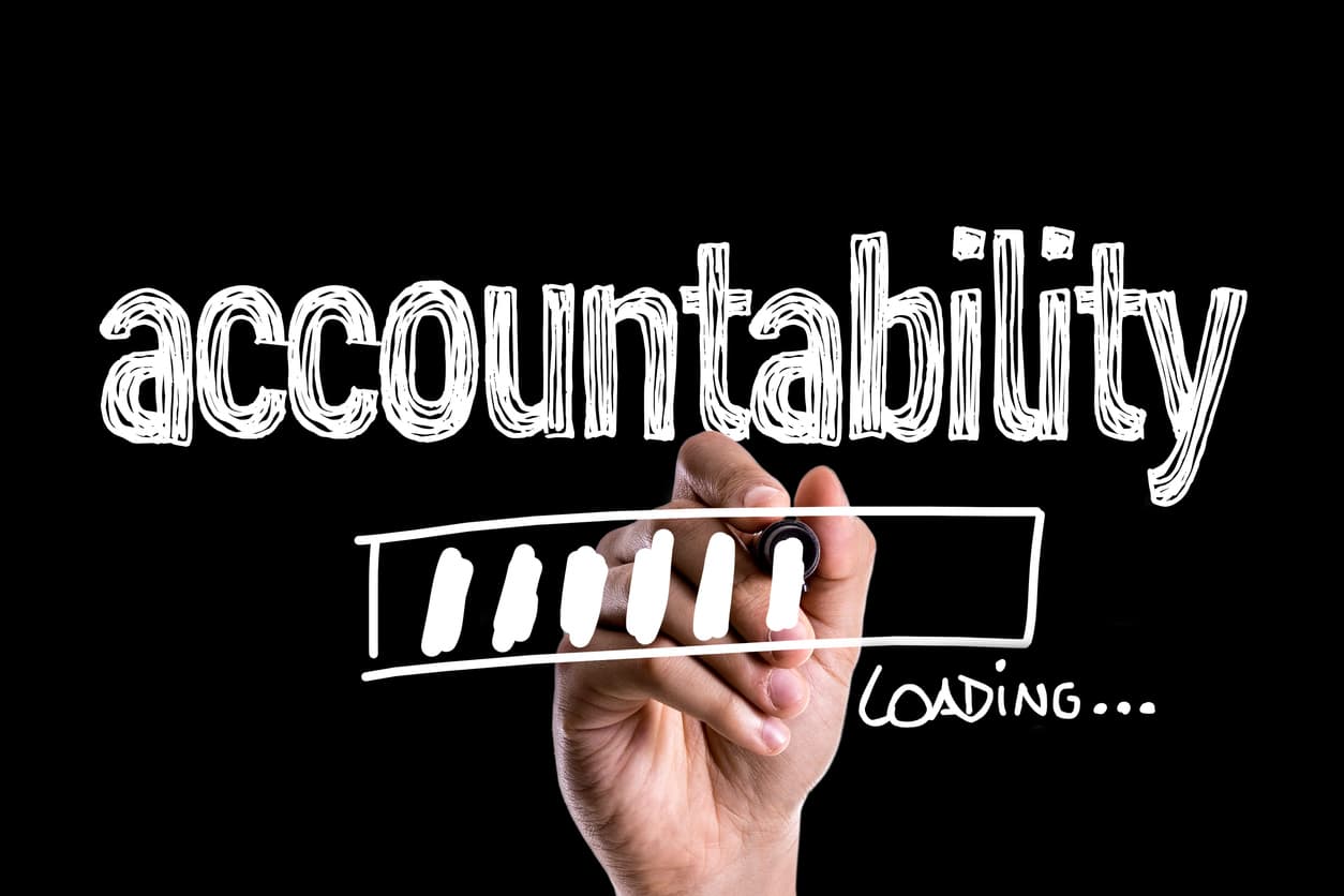 A hand draws the word accountability.