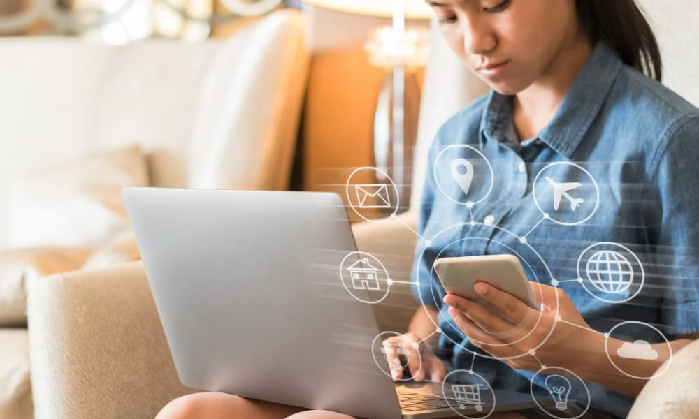 A woman using a laptop and a smartphone for automated training.