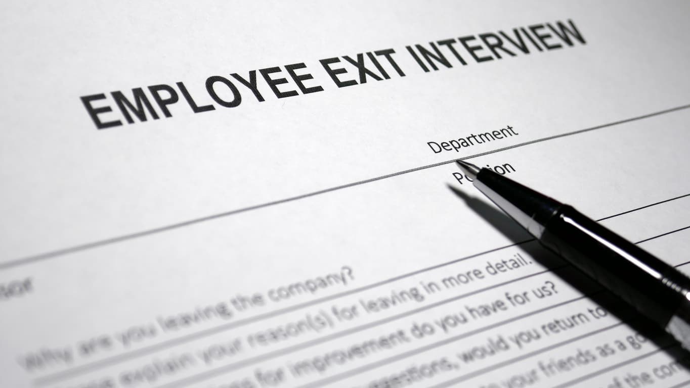 Employee filling out a form for exit interviews, which includes black text on white copy paper.
