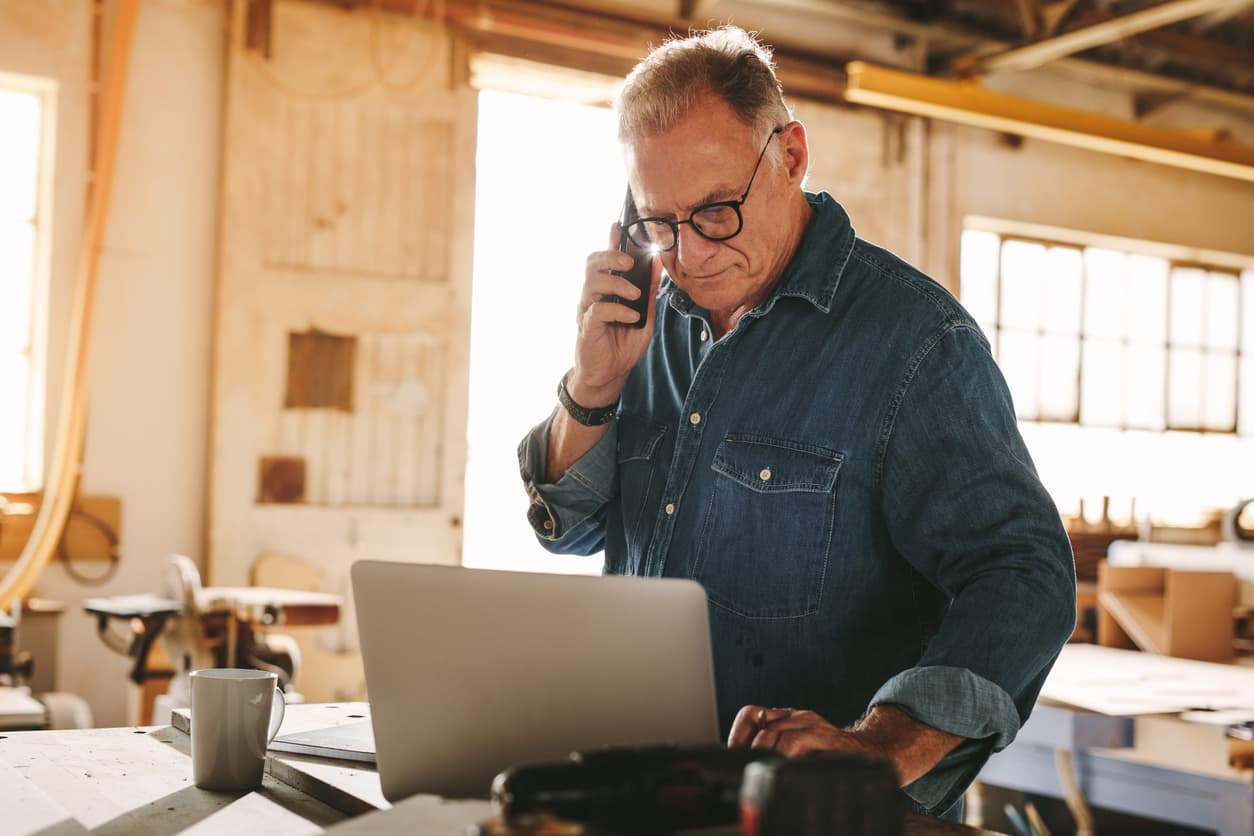 Older man on the phone in front of a computer 