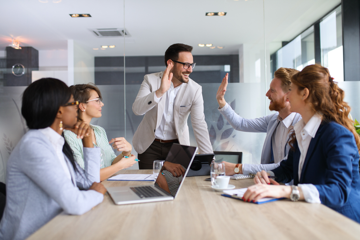 Two men high-five each other at a business conference and celebrate how MetaGrowth set their sales team up for success.