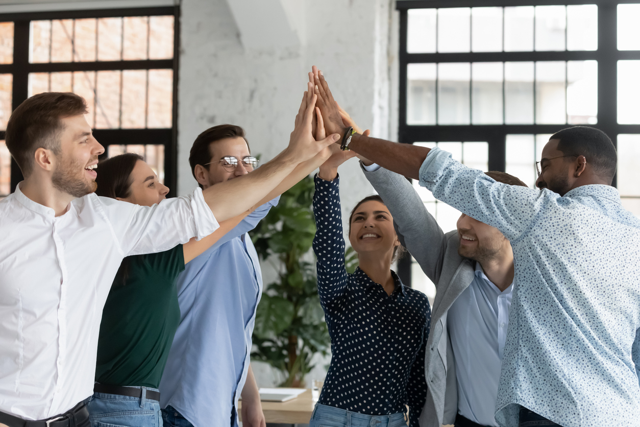 A diverse group of employees high fives each other and celebrates ways to equip their sales team for success.