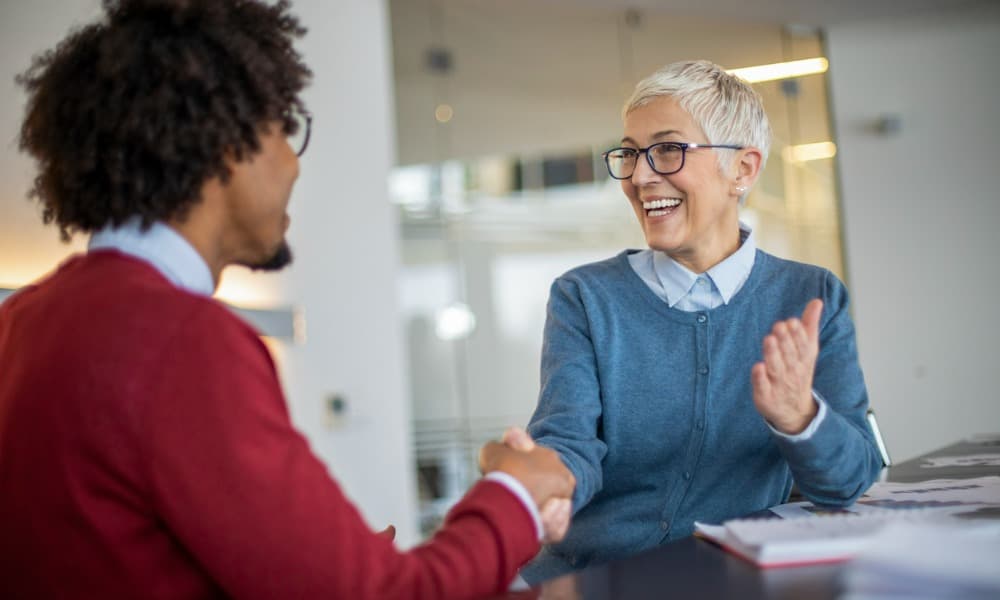 A job candidate and prospective employer laughing during a job interview.