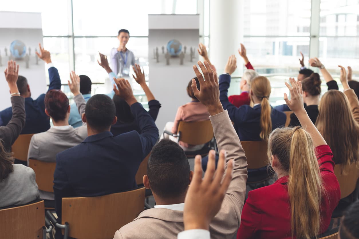 salespersons raising their hands to volunteer during sales team training