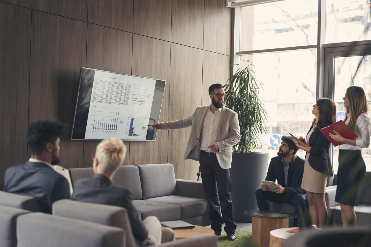 A team leader shows his team charts about sales enablement, technology, and strategy needed to support your sales team in 2021 and beyond.