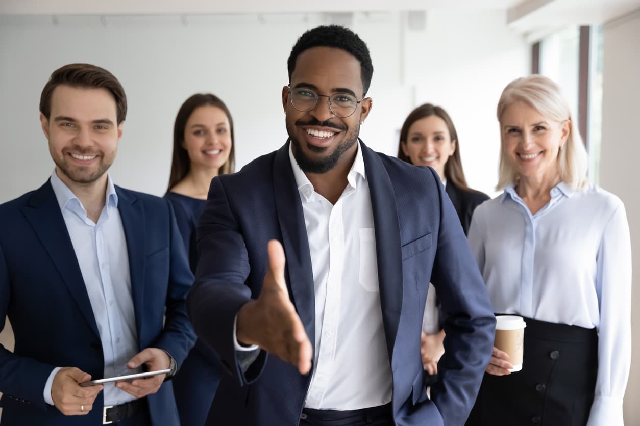 A sales enablement team whose leader is stretching their hand forth for a handshake