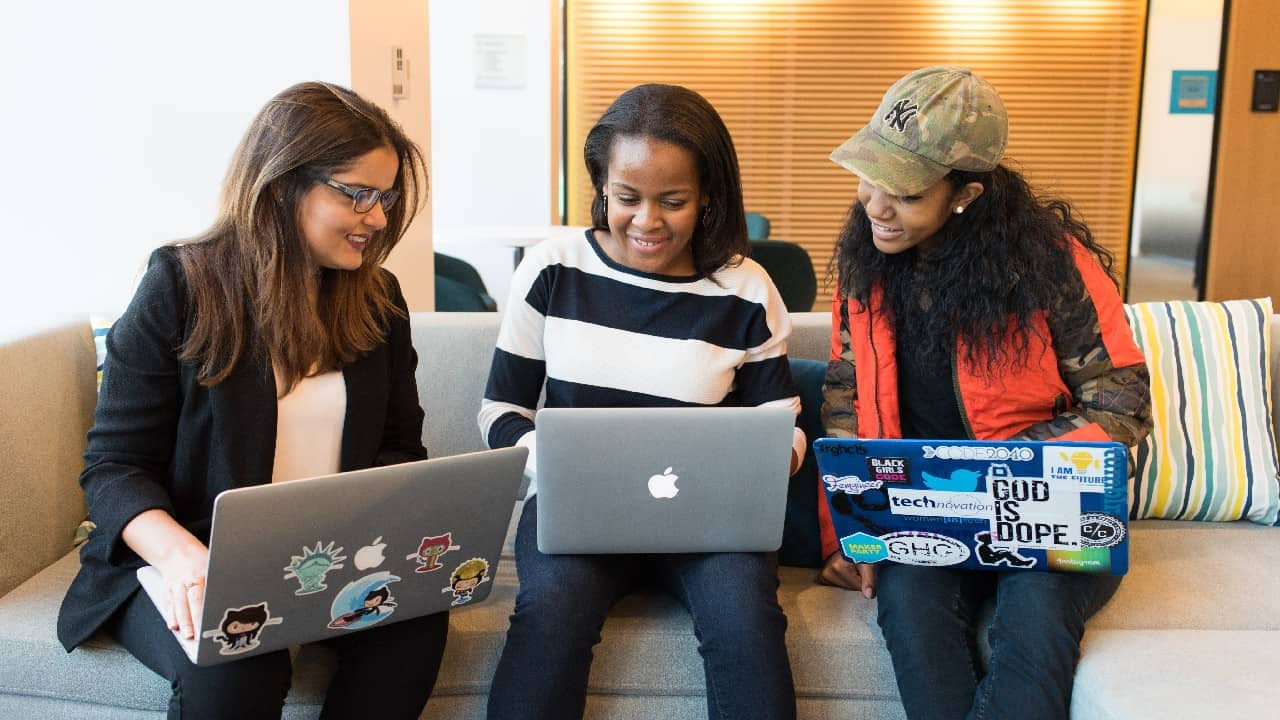 Three women sitting and looking at laptops