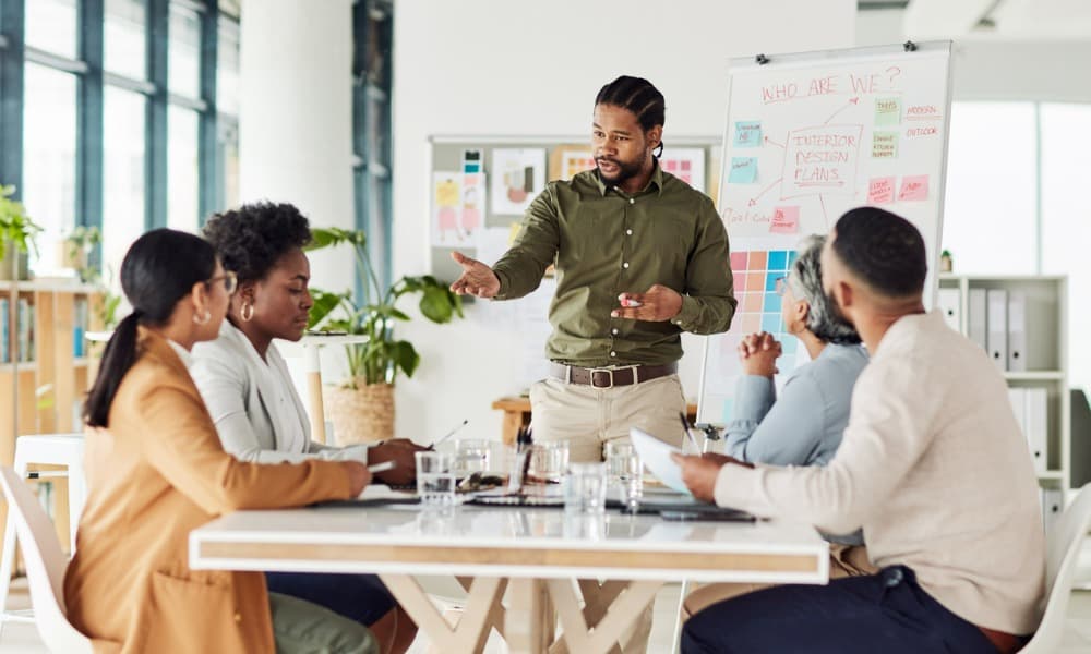 A sales manager addressing a diverse group of team members sitting around a table.