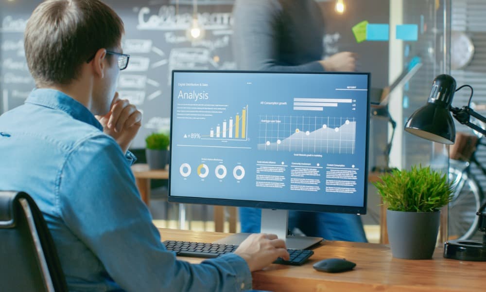 A man working on a computer with sales performance graphs.