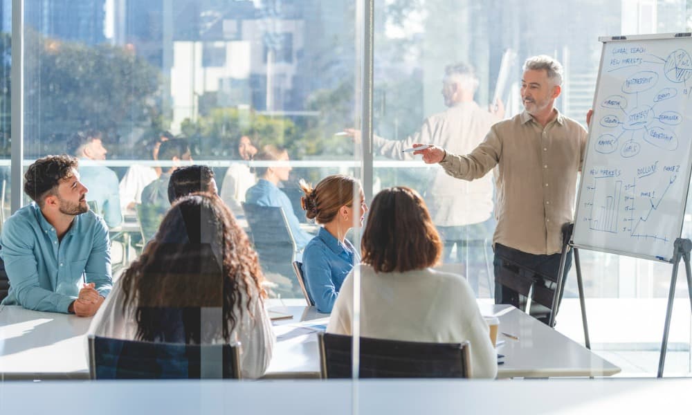 A business owner conducting training for sales in a full conference room.