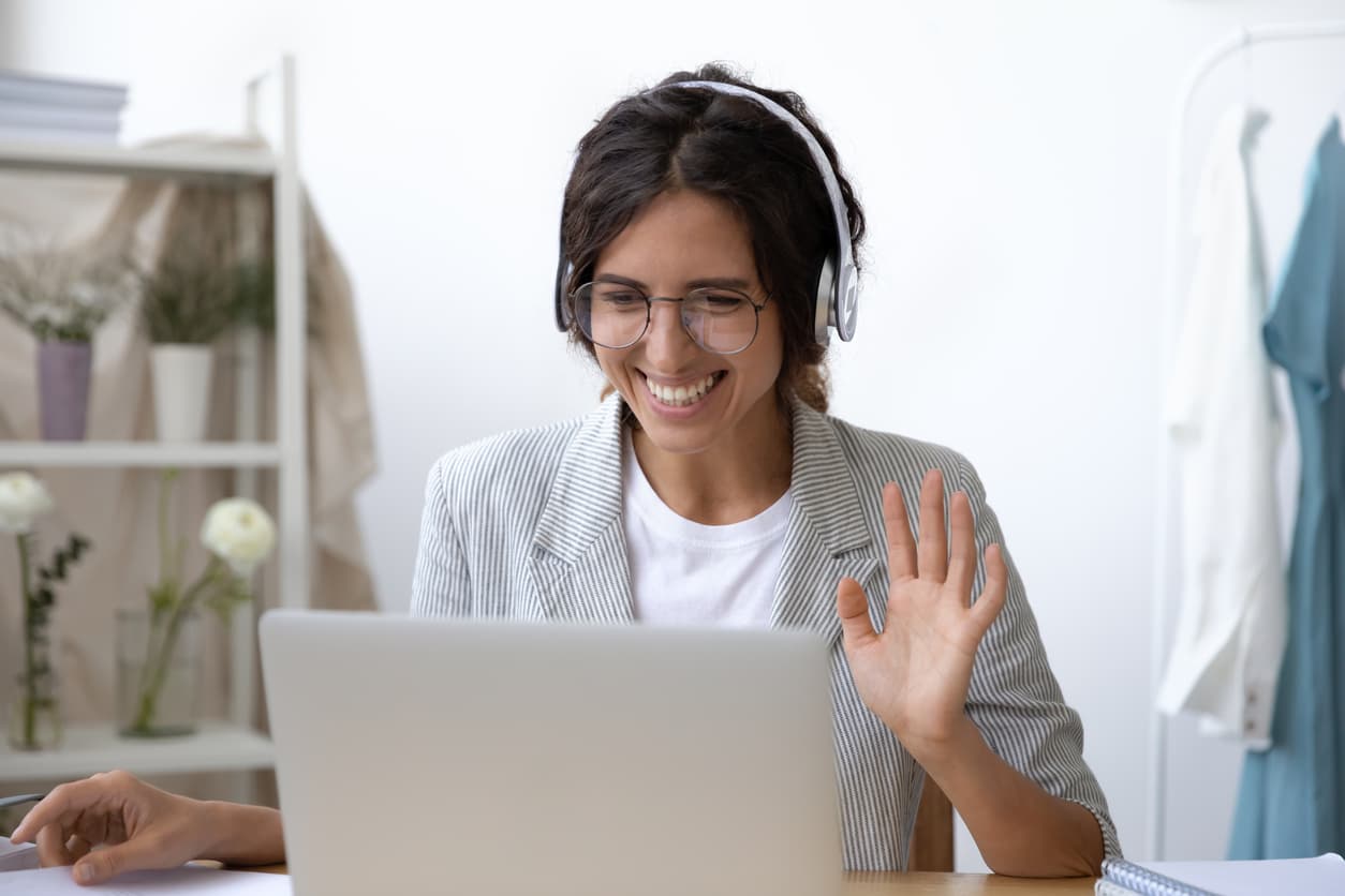 Saleswoman in a headset taking part in a virtual sales team building activity through her laptop
