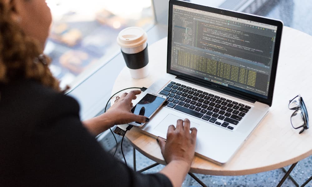 Woman with phone sitting in front of a laptop